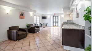 A spacious lobby with a reception desk, seating area, and a large window. - Motel 6 Hazelwood, MO (Hazelwood)