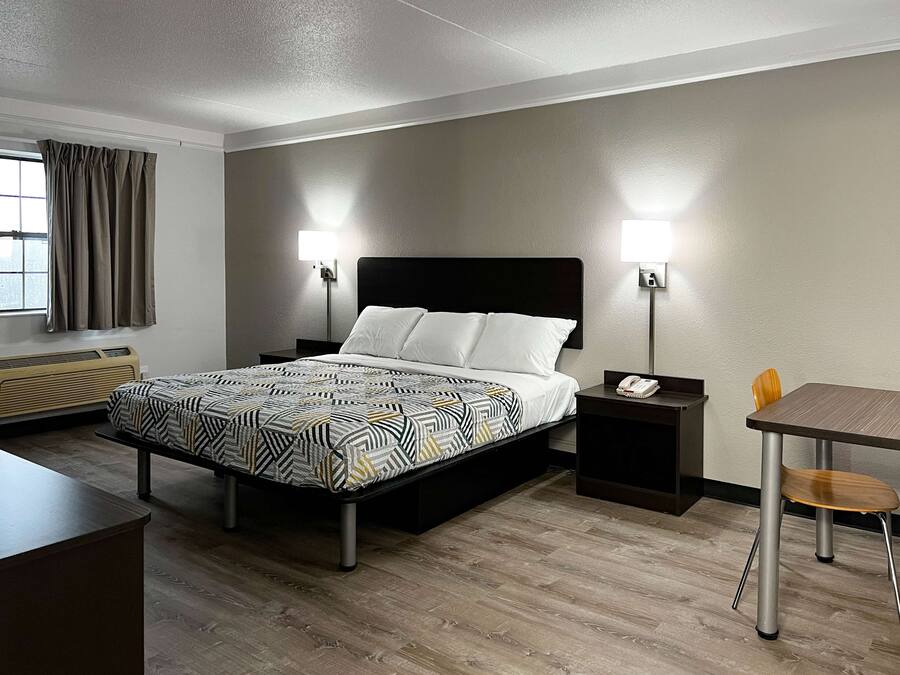 A hotel room with a bed, bedside tables, a desk, and a chair.