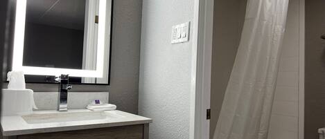 A bathroom with a sink, mirror, and shower curtain.