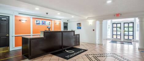 A reception area with a reception desk, a black doormat, and a tiled floor.