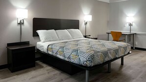 A modern hotel room with a large bed, bedside lamps, a desk, and a chair. - Motel 6 Hazelwood, MO (Hazelwood)