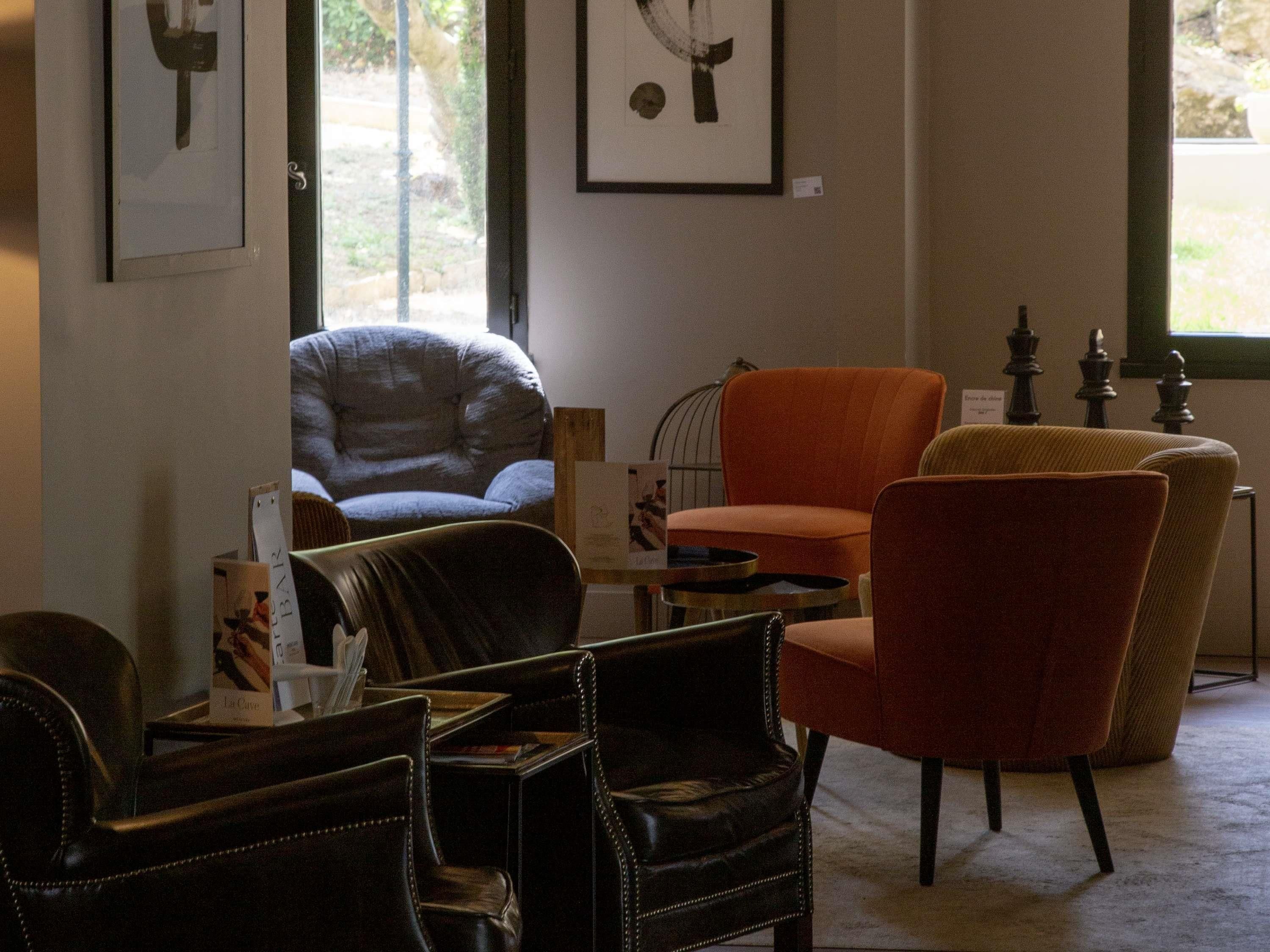 Una habitación con sillones de cuero, un sillón azul y una mesa con un libro y una caja.