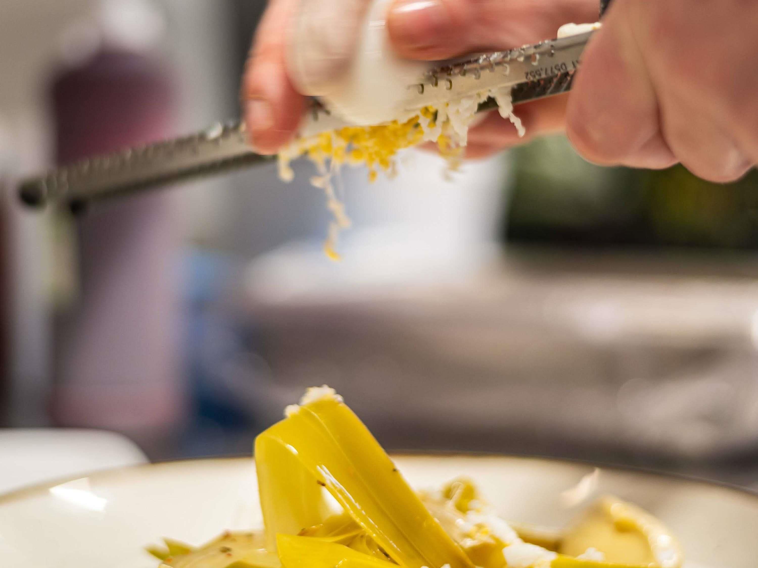 A person grating cheese on a plate.