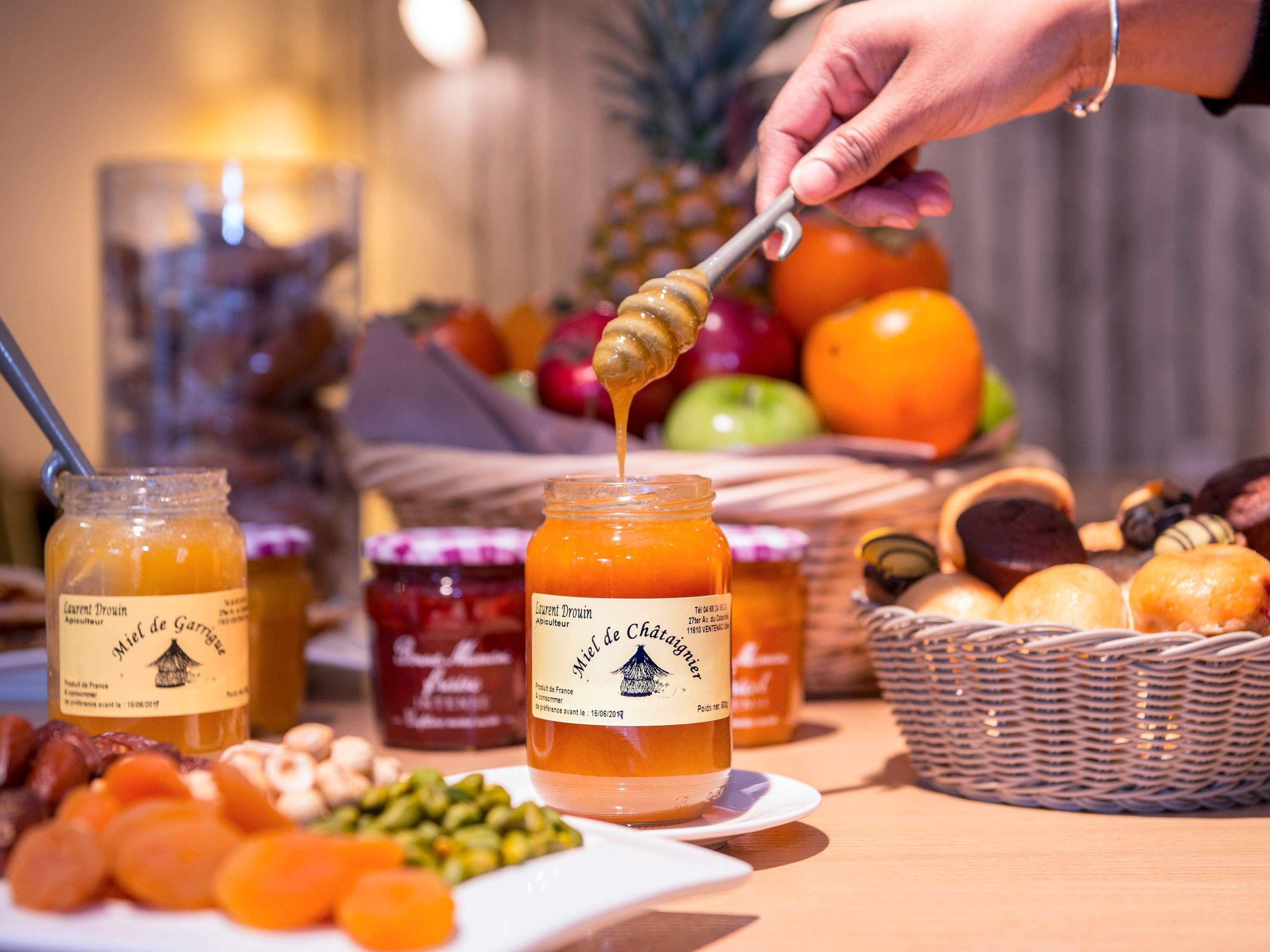 A table with jars of honey, fruits, and nuts.
