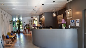 Un área de recepción con mostrador curvo, zona de estar con sillas y un ventanal que proporciona luz natural.