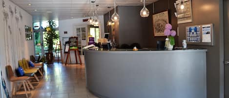 A reception area with a curved counter, a seating area with chairs, and a large window providing natural light.