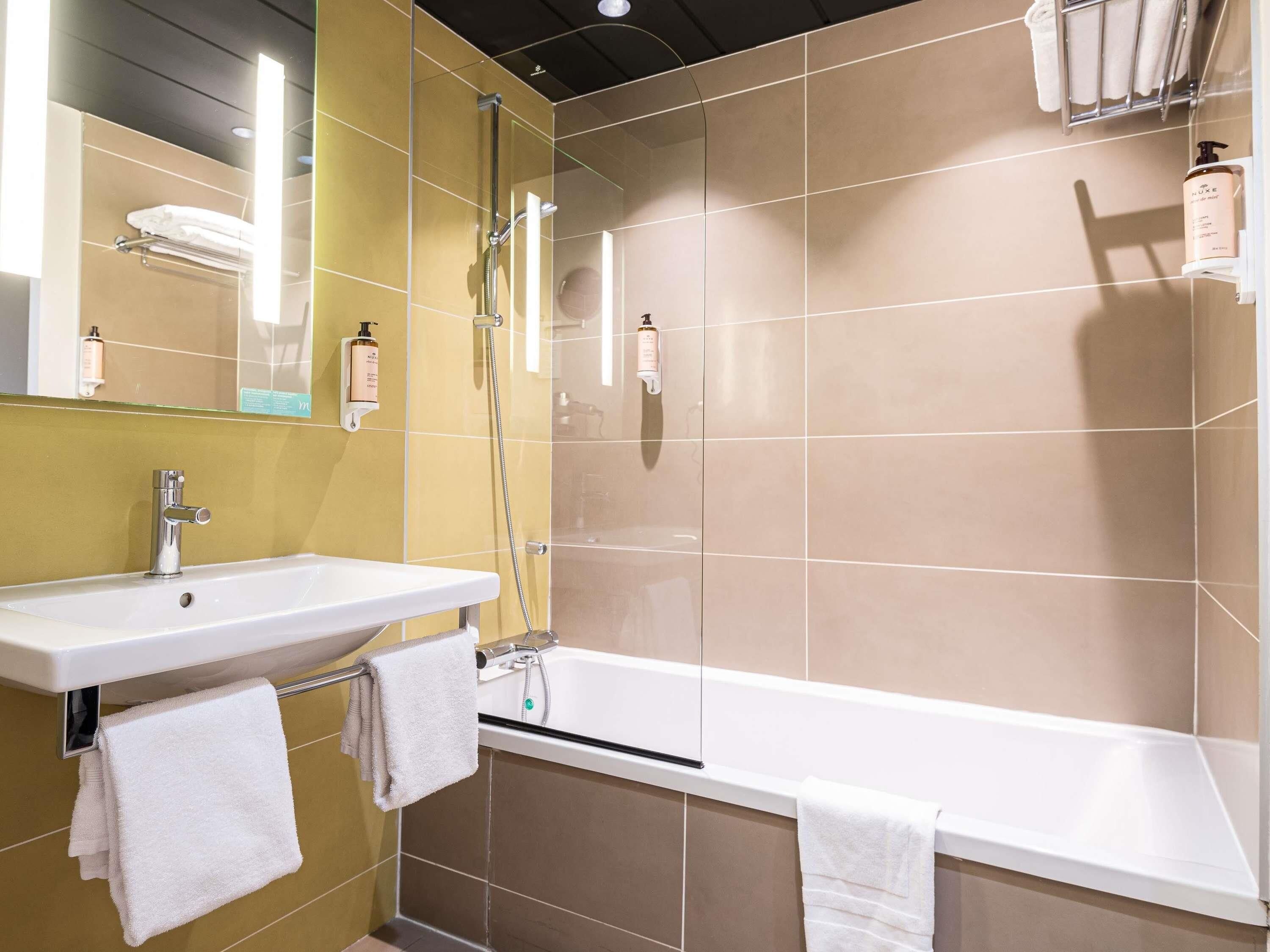 Een badkamer met een wit wastafel, een badkuip en een douche.
