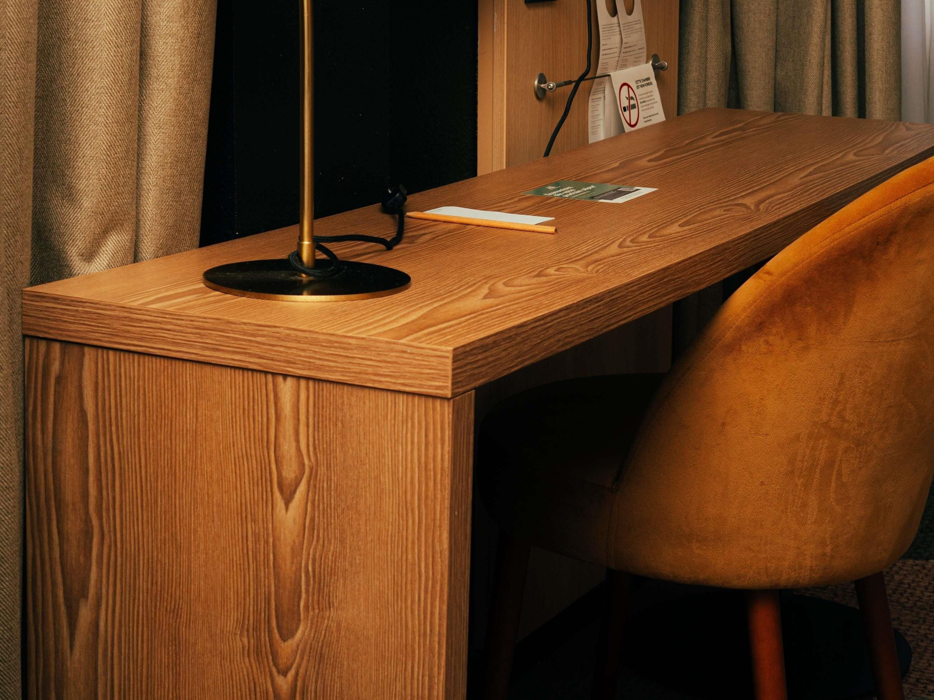Una scrivania in legno con una lampada, una sedia e una porta con un cartello.