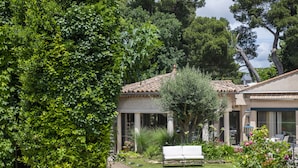 Un jardín con un banco blanco, un camino y un edificio con techo de tejas.