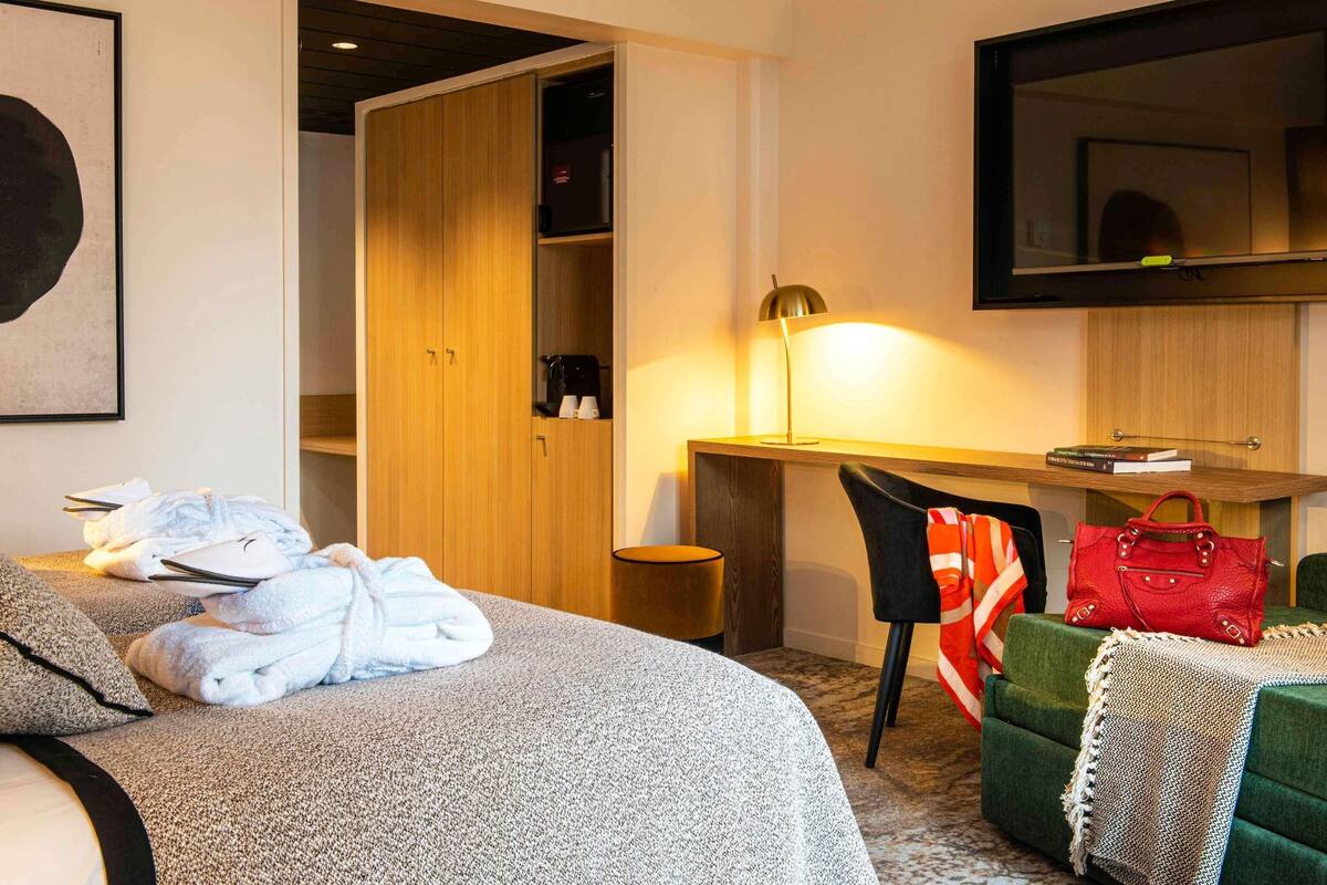 Ein Hotelzimmer mit Bett, Schreibtisch, Stuhl, Kleiderschrank und Spiegel.