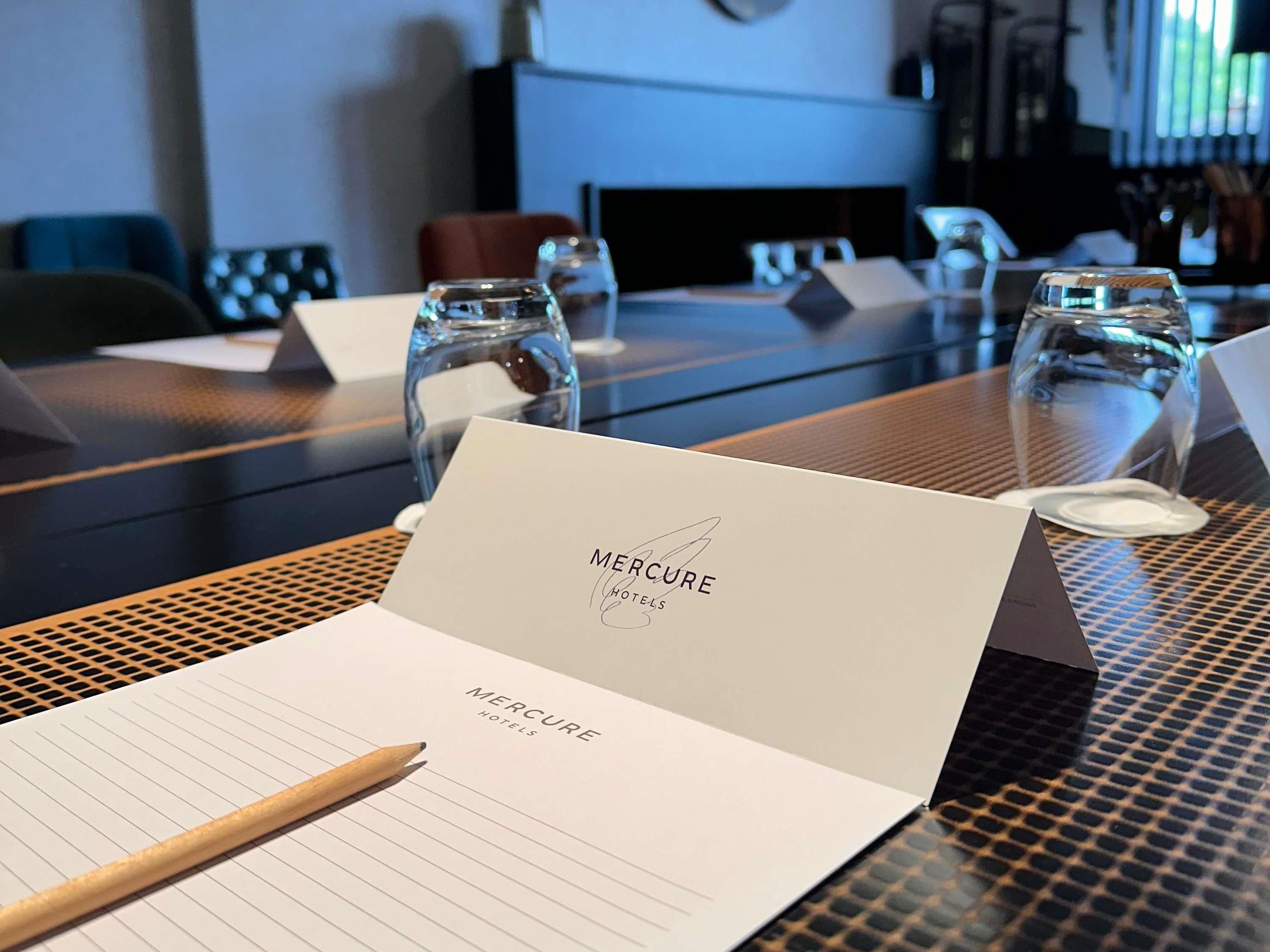 Une chambre d’hôtel avec une table mise pour un repas, un bloc-notes et un stylo.