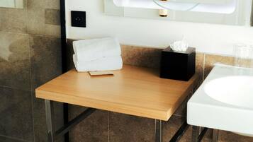 A bathroom with a wooden vanity, a white sink, and a towel on the counter.