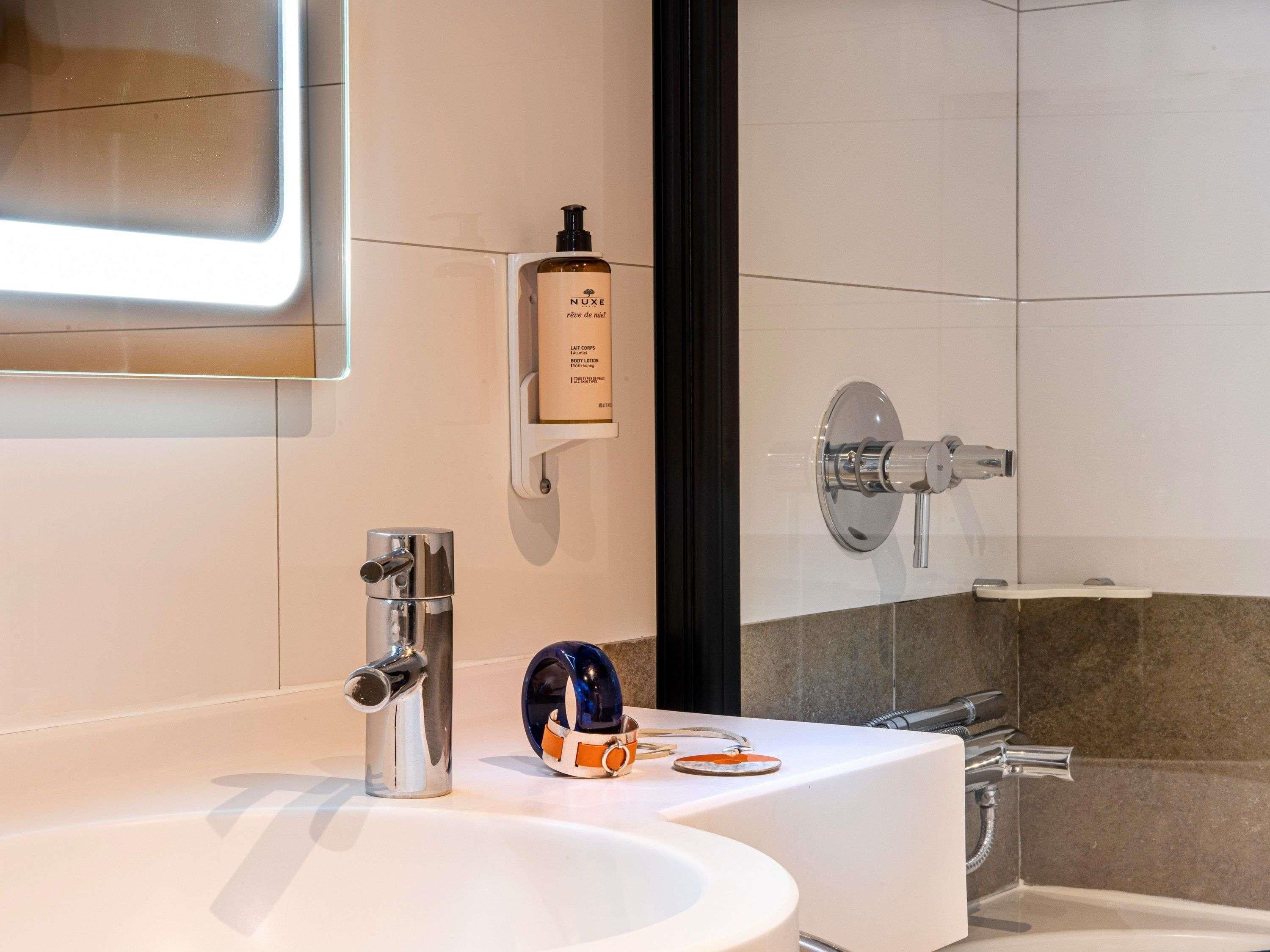 A modern bathroom with a large mirror, a sink, and a shower area.