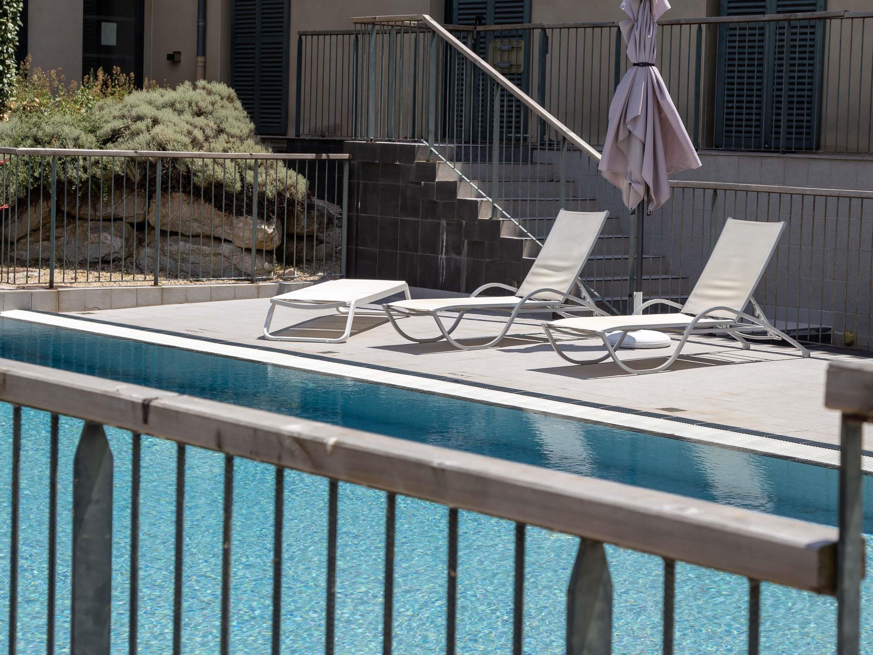 A pool area with lounge chairs and a pergola.