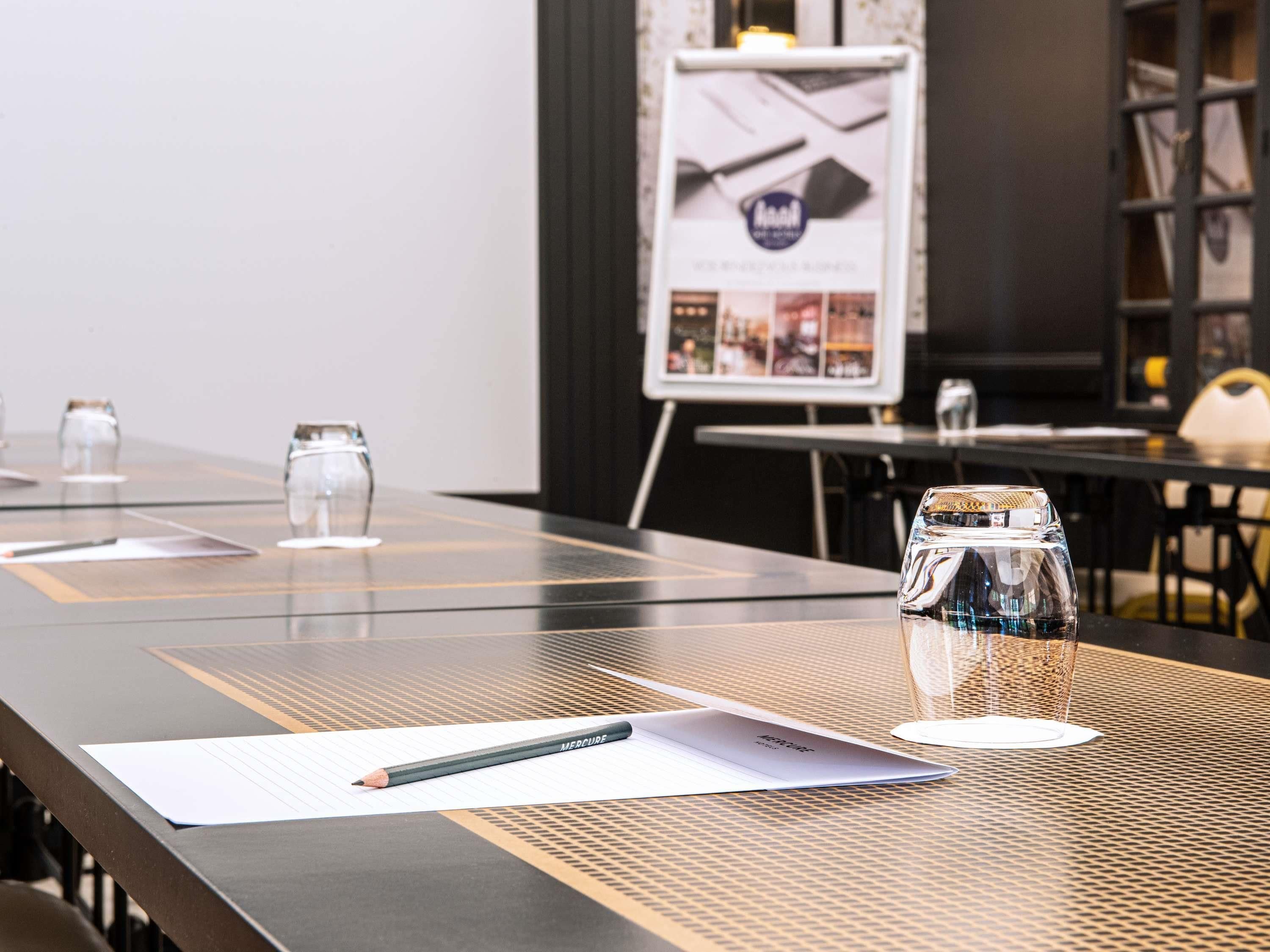 A conference table with a notebook, pencil, and glass jar.