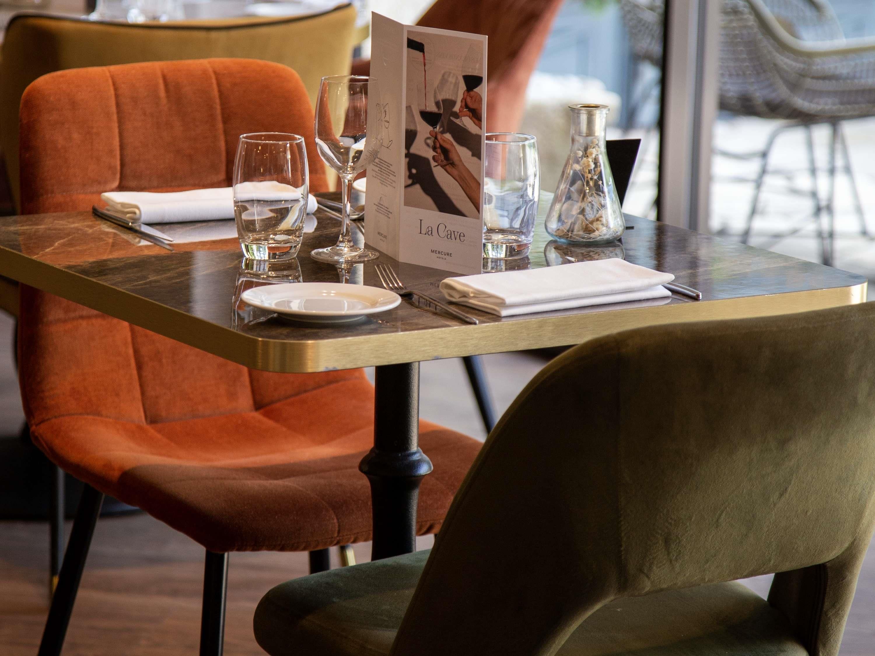 A dining table with a menu, glasses, and a bottle of water.