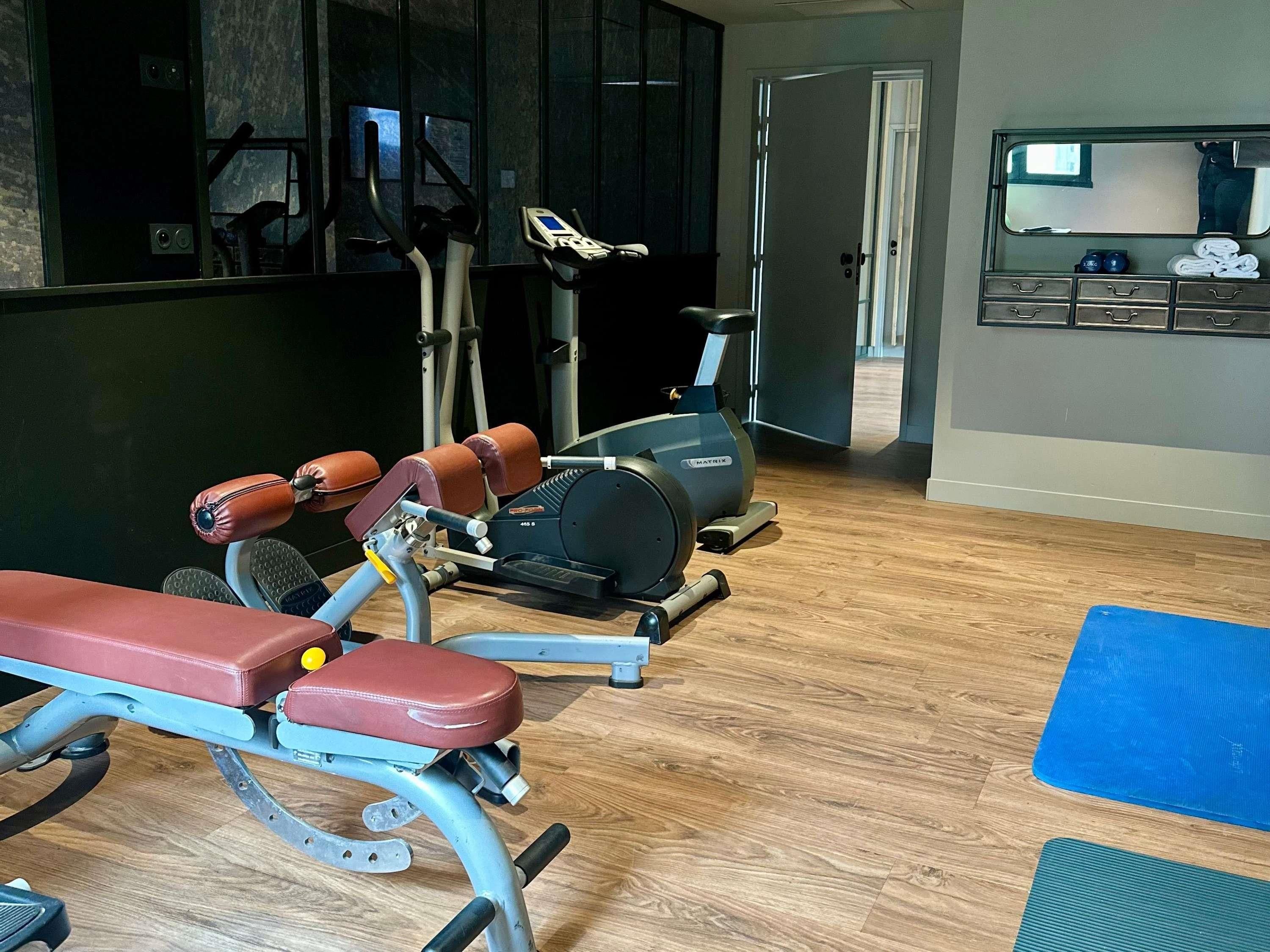 A gym with a bench press, an elliptical, and a treadmill.