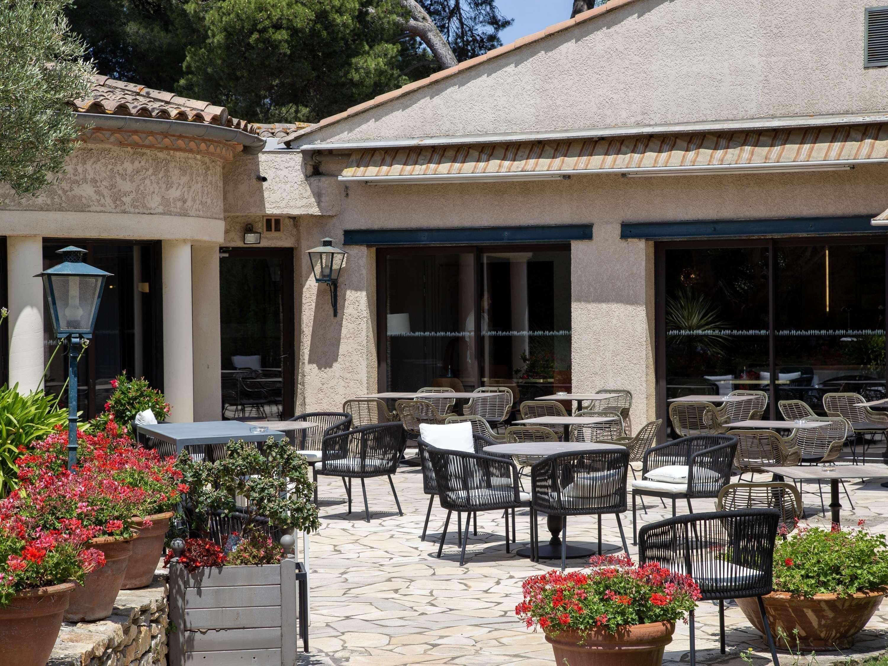 An outdoor patio area with stone flooring, wicker furniture, and potted plants.