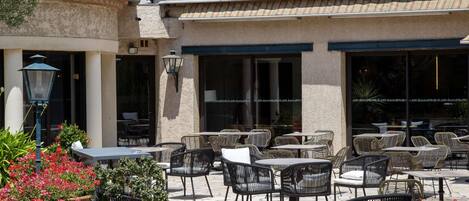 An outdoor patio area with stone flooring, wicker furniture, and potted plants.