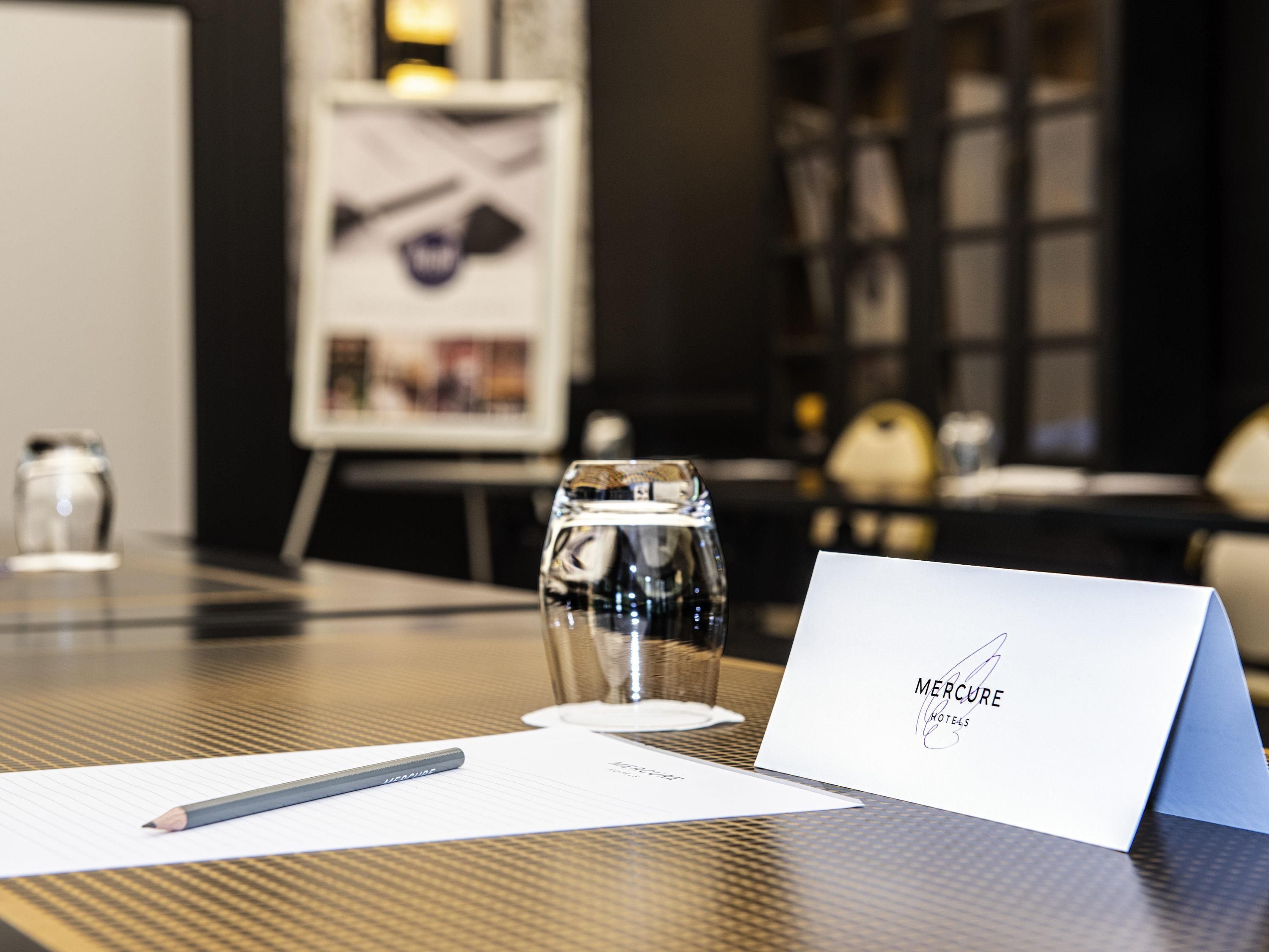 A hotel reception desk with a glass of water, a pen, and a business card.