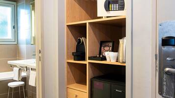 Un bagno compatto con lavandino, uno sgabello, un portascopevoli, un forno a microonde, un bollitore e un piccolo frigorifero.