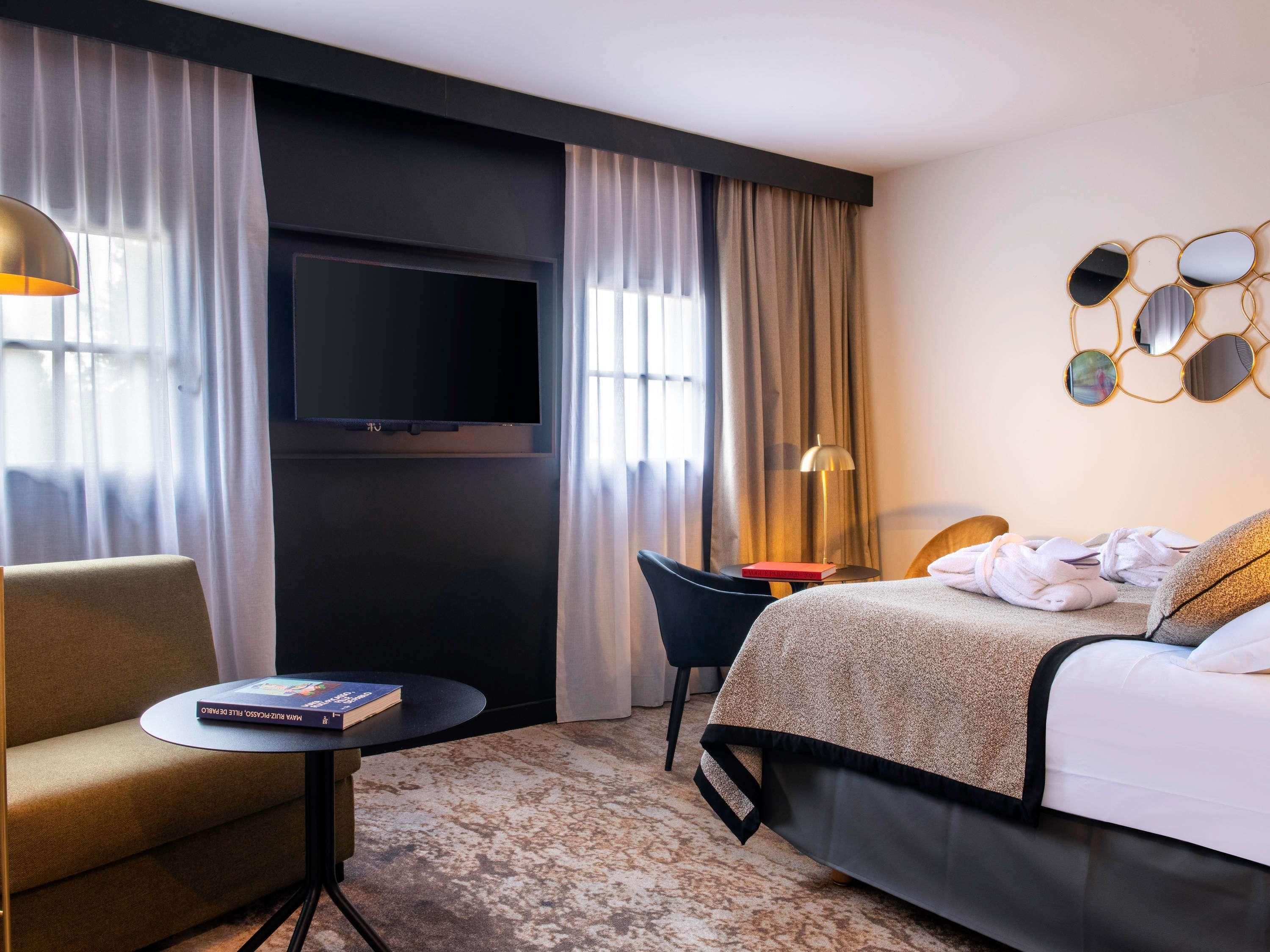Ett hotellrum med en säng, en tv, ett skrivbord och en stol.