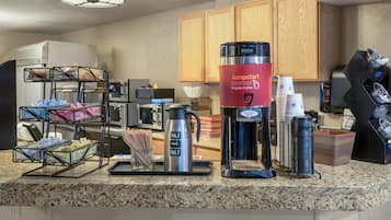 A kitchen area with a coffee station, including a coffee maker, a kettle, and a coffee dispenser.