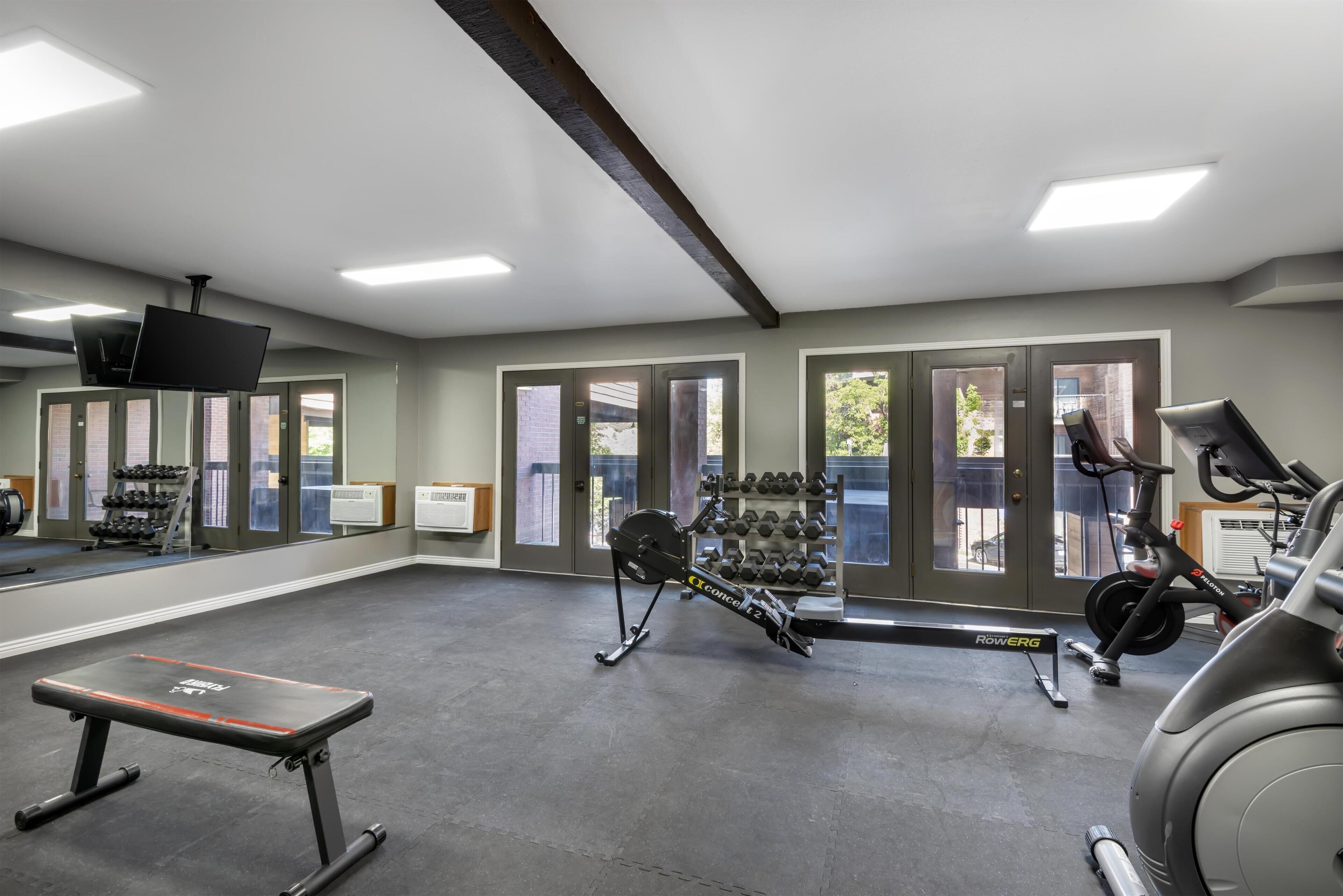 Une salle de sport équipée de matériel d’exercice, d’un banc et d’un miroir.