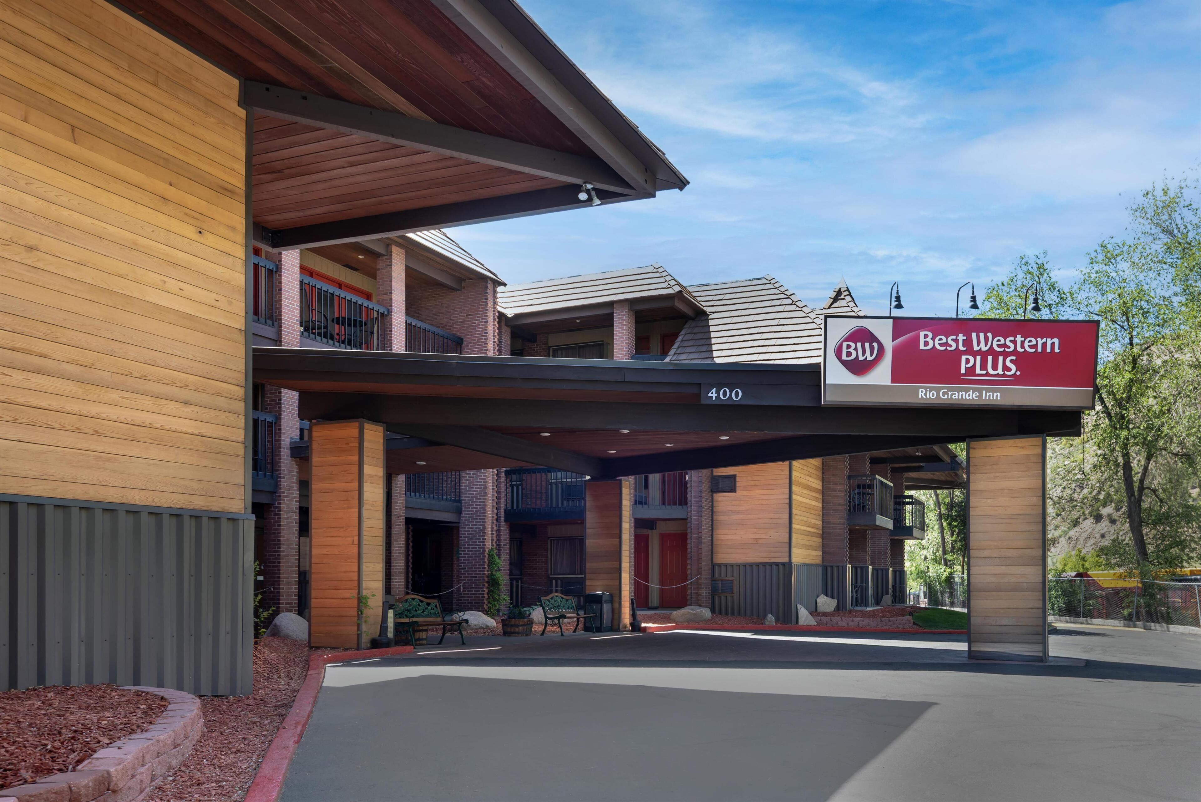 A hotel entrance with a covered walkway, outdoor seating, and a sign for Best Western PLUS Rio Grande Inn.