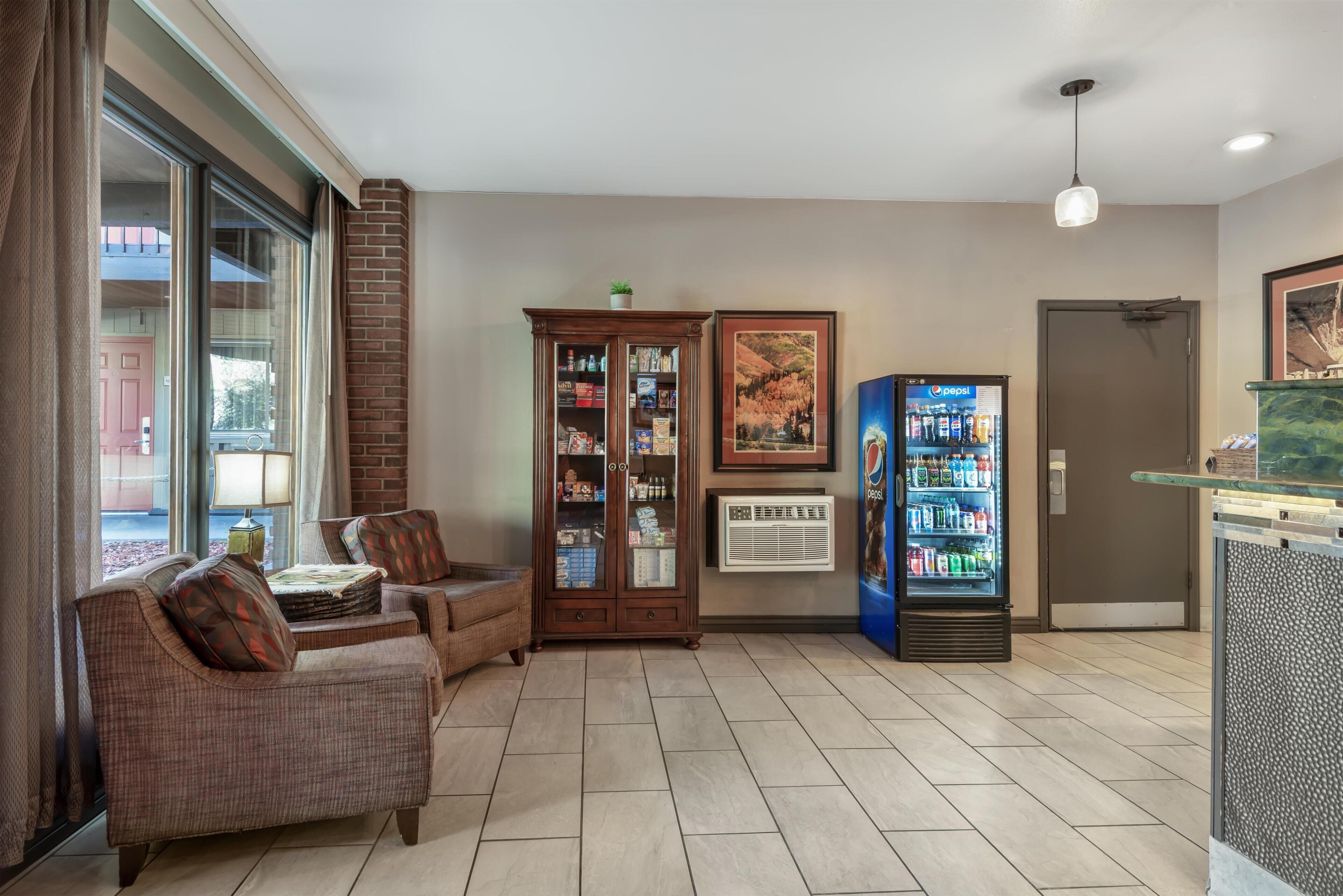 A lobby with a seating area, a beverage dispenser, a cabinet with items, and a door.