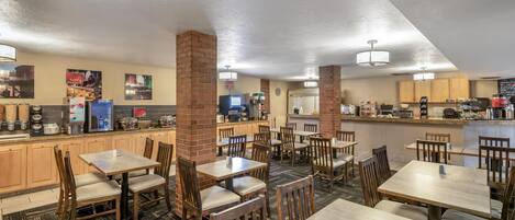 Un restaurante con varias mesas y sillas, una zona de cocina y un mostrador.