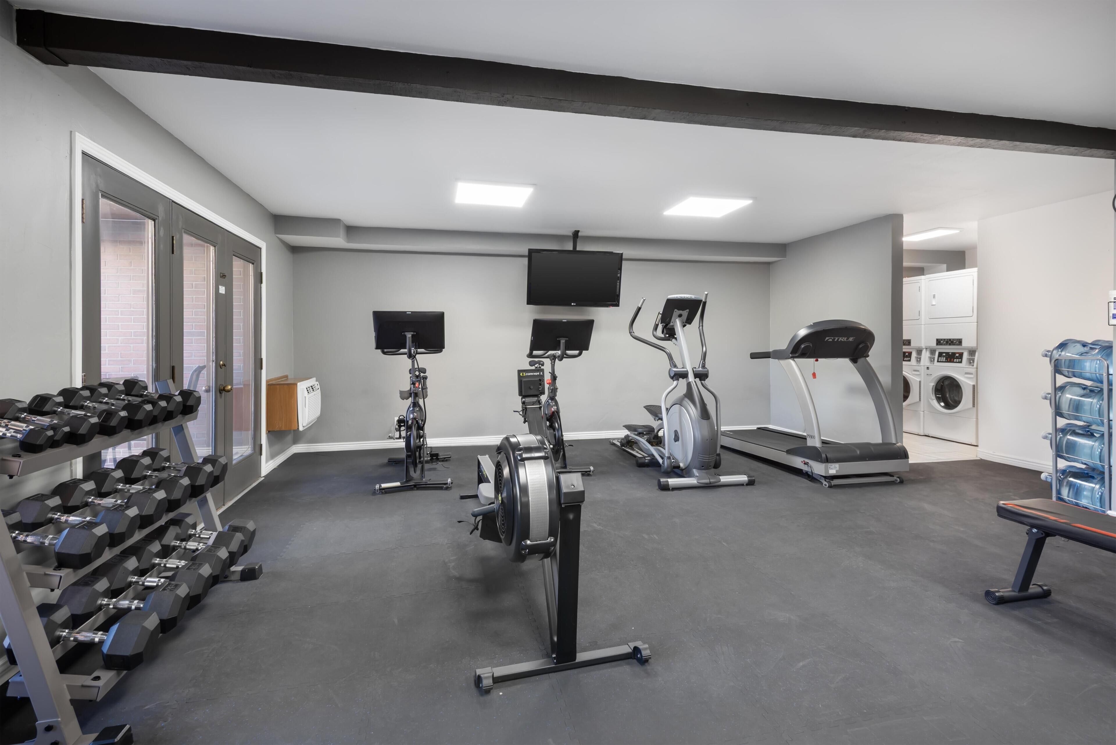 Une salle de sport équipée d’haltères, de machines de cardio et d’un téléviseur.