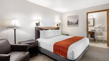A hotel room with a bed, bedside tables, a chair, a desk, and a mirror.