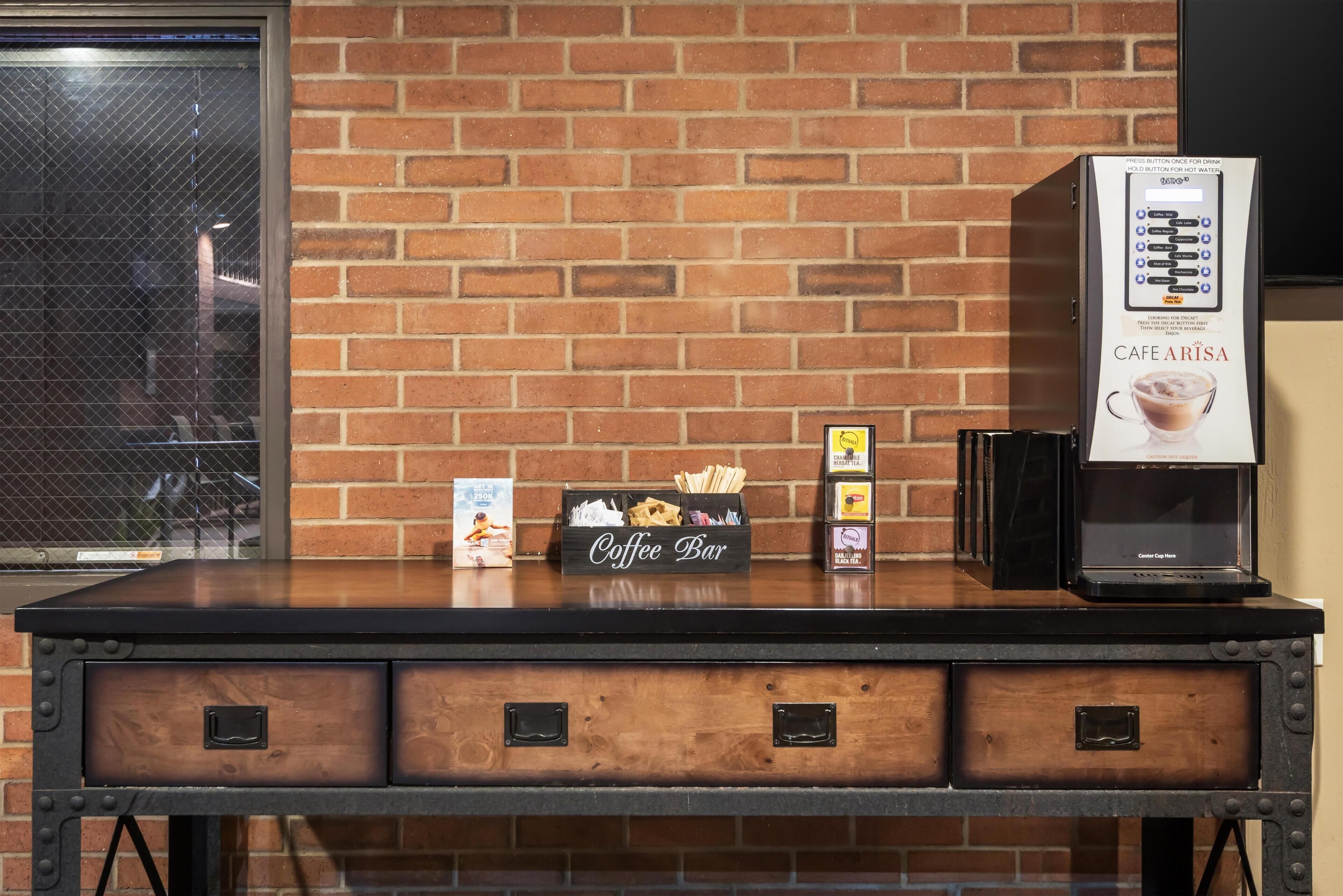 A coffee bar with a branded coffee machine, a box of coffee beans, and a coffee menu.