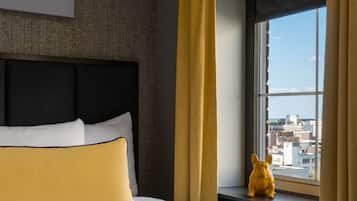A hotel room with a bed, a view of the city through a window, and a decorative item on the windowsill.