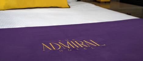Ein Bett mit einer violetten Bettdecke und einem gelben Kopfkissen.