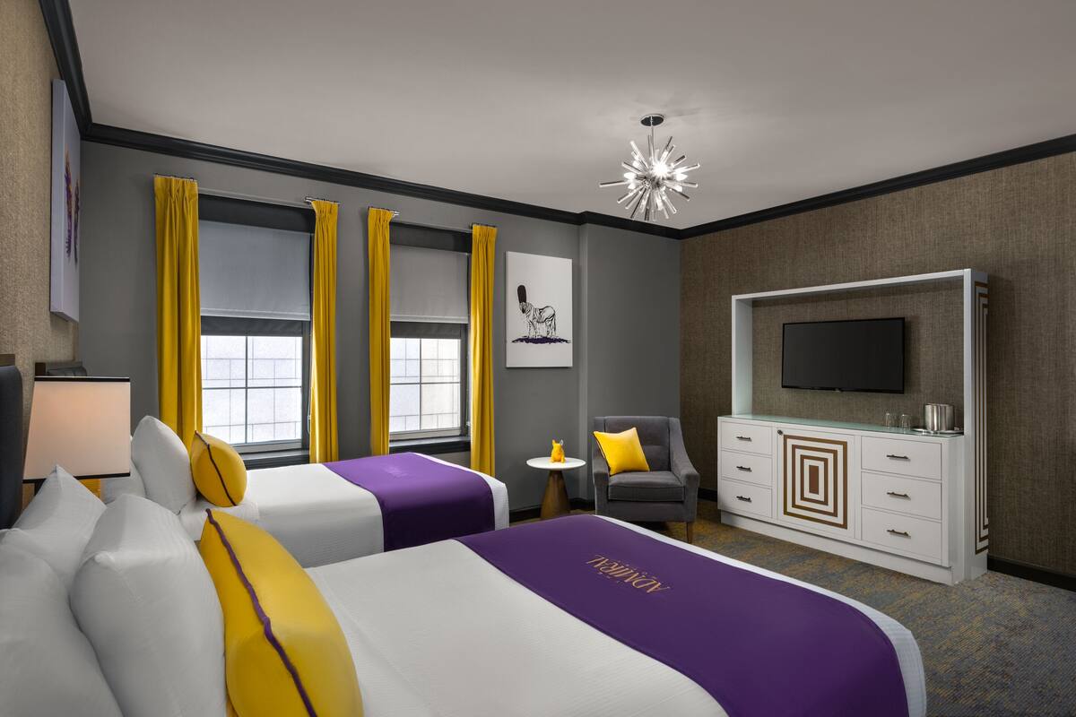 Una habitación de hotel con dos camas, un televisor, una mesita y una silla.