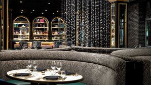 A luxurious bar area with a high ceiling, elegant seating, and a well-stocked bar.