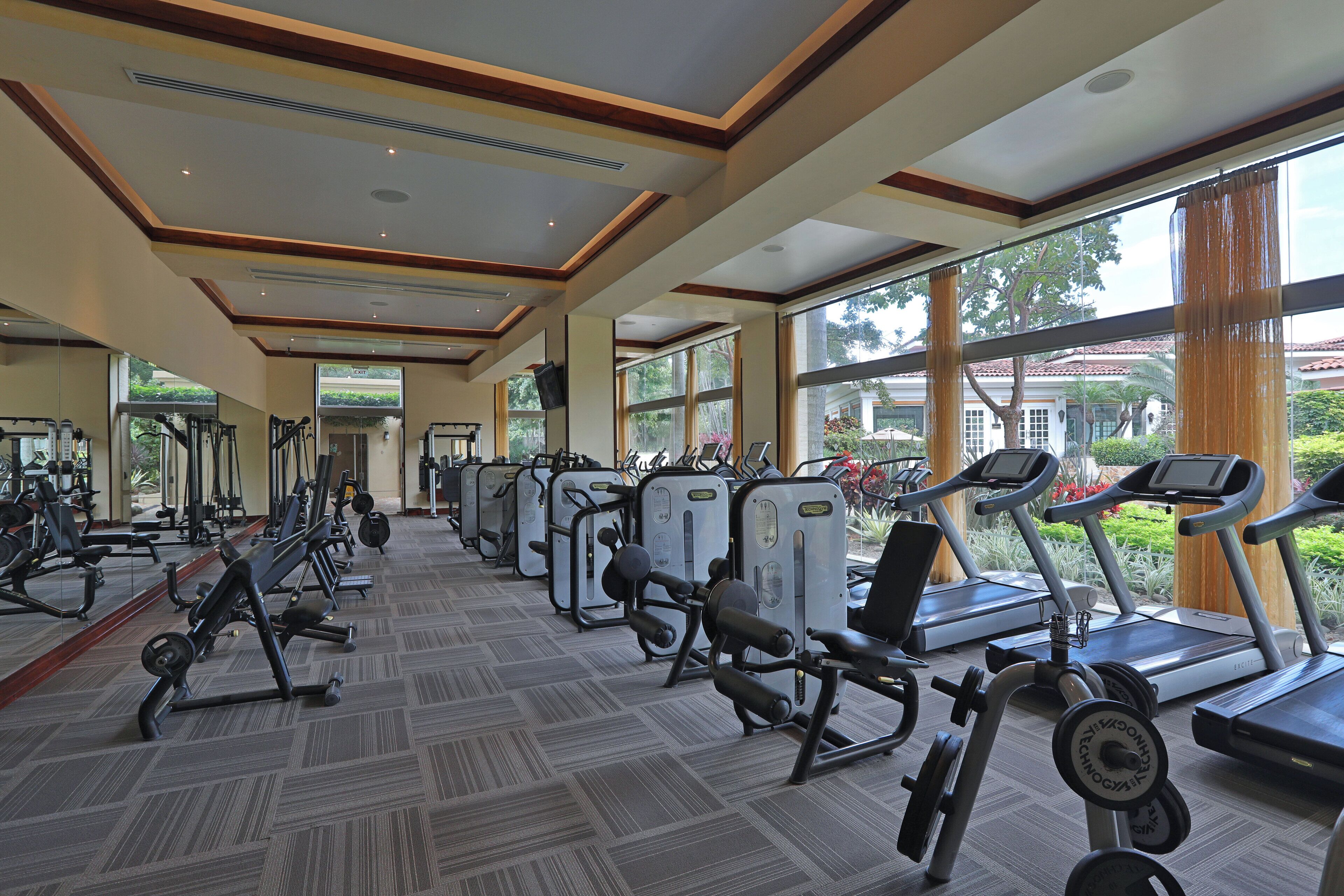 A gym with cardio machines, weight stations, and mirrors.