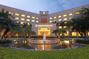 A hotel with a central fountain, surrounded by palm trees and well-maintained greenery. - InterContinental Costa Rica at Multiplaza Mall by IHG (San Rafael)