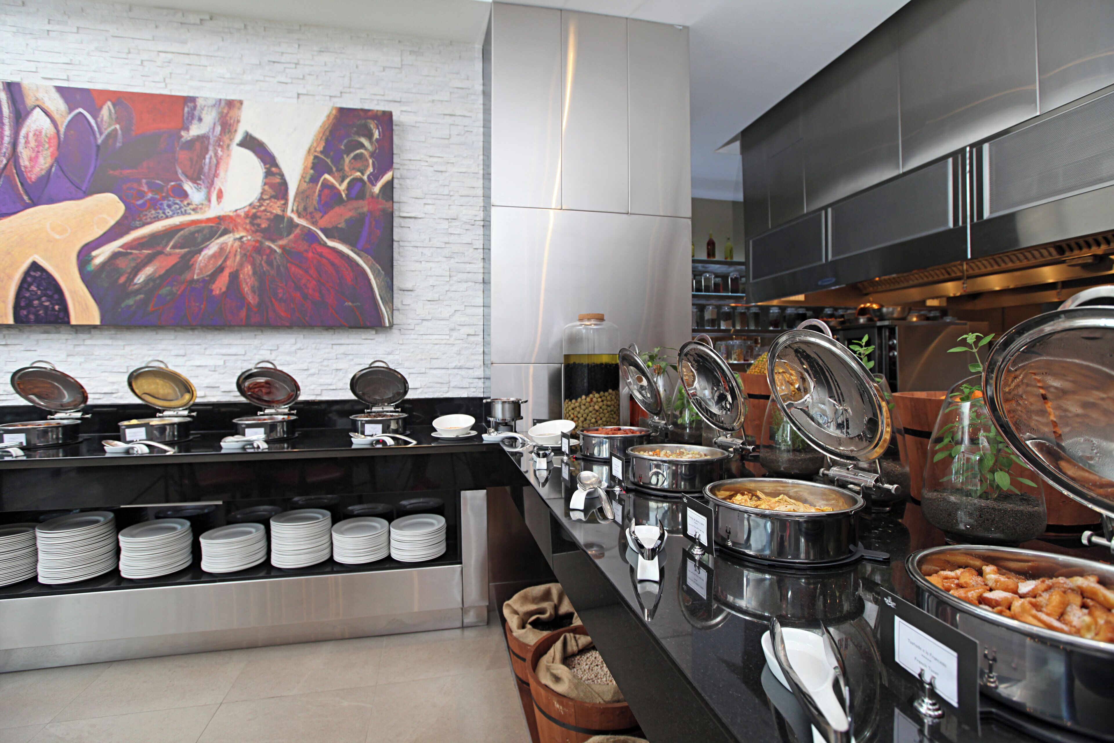 A buffet setup with various food containers and a decorative wall piece.
