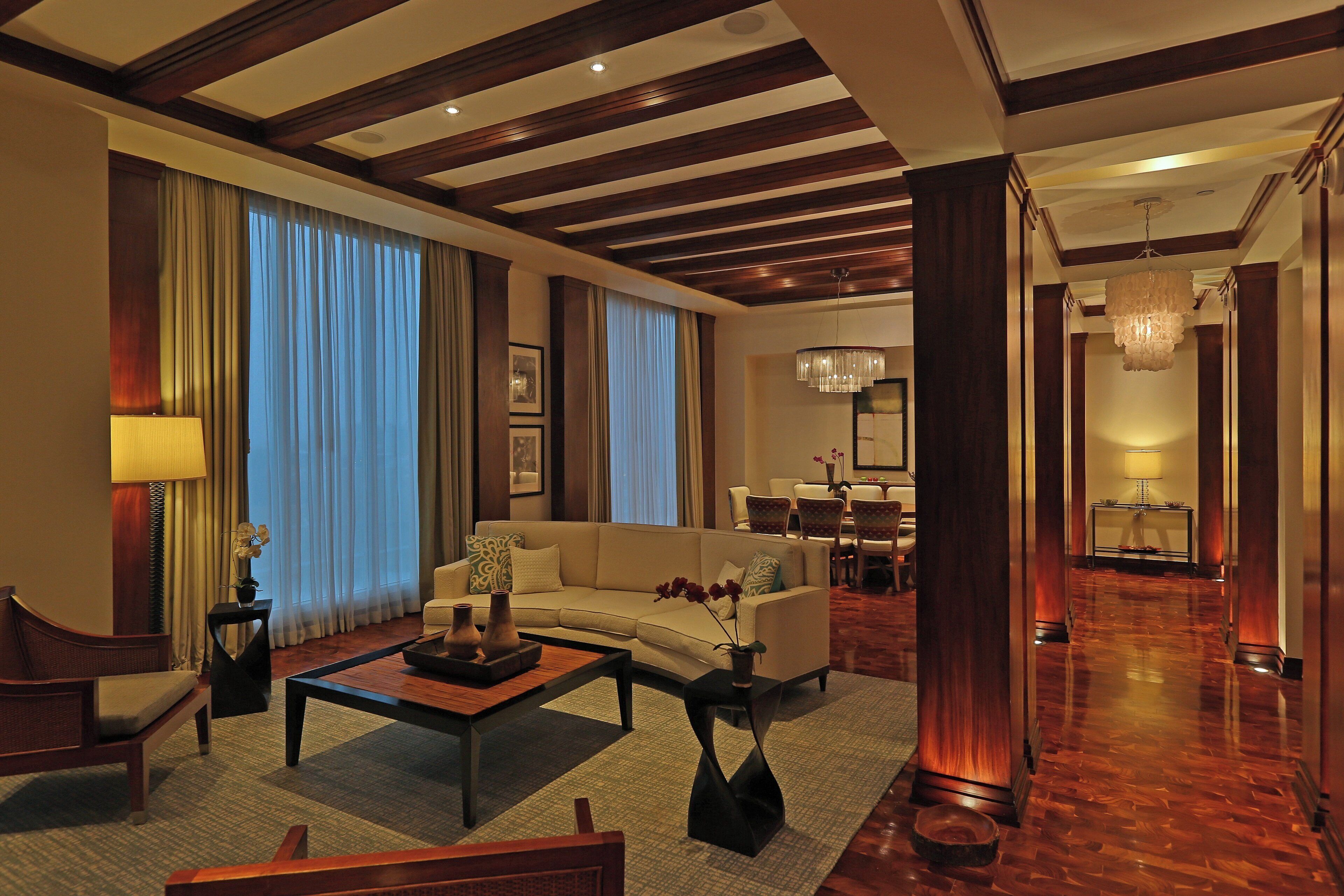 A spacious living room with a sofa, coffee table, and a dining area in the background.