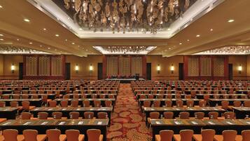 A large conference room with rows of tables and chairs, a patterned carpet, and a decorative ceiling.