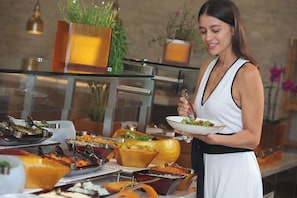 A buffet setup with various food items and a person serving themselves. - InterContinental Costa Rica at Multiplaza Mall by IHG (San Rafael)