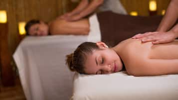 A massage therapy room with two massage tables, one occupied by a client and another with a therapist.