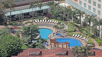 Um resort com uma grande piscina, espreguiçadeiras e palmeiras.