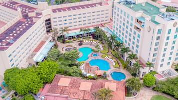 A hotel with multiple swimming pools, a rooftop bar, and lush landscaping.