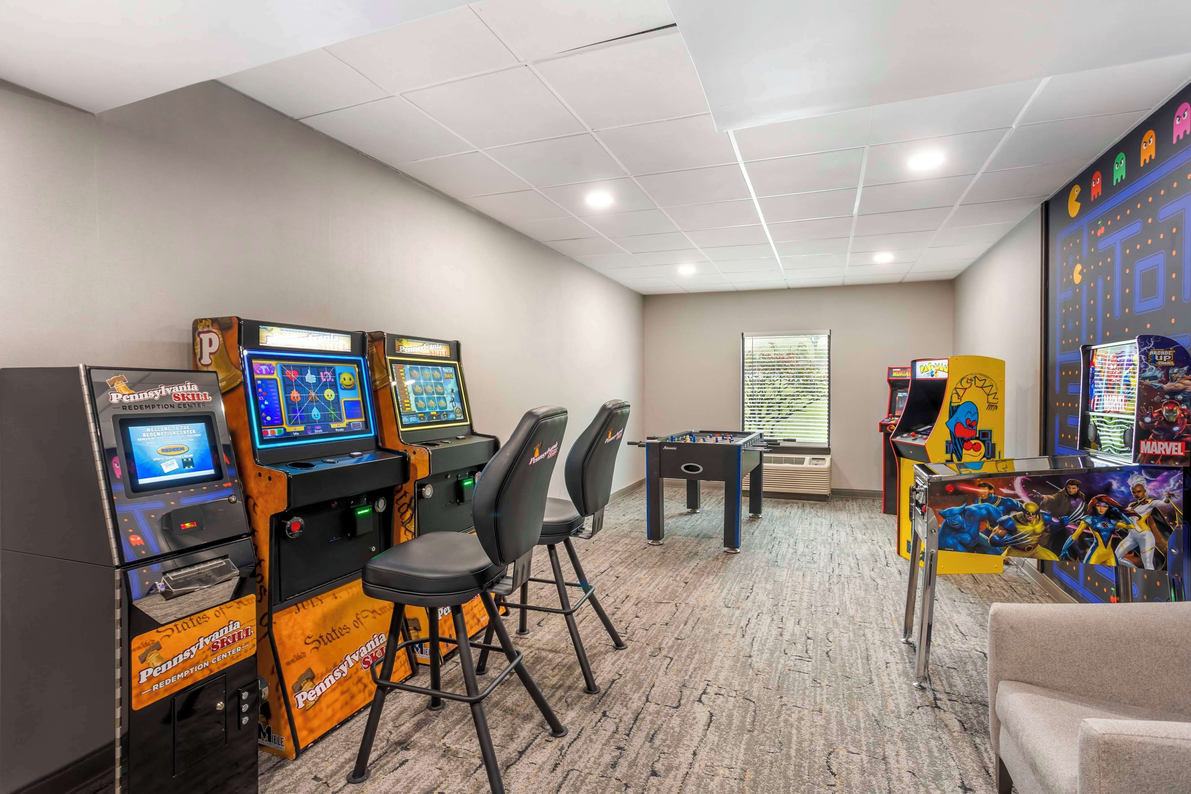 A room with arcade games, a foosball table, and a Marvel-themed display.