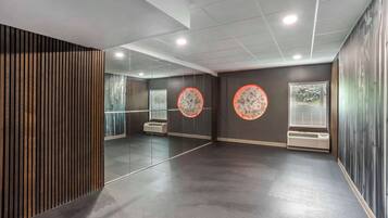 Une pièce moderne et bien éclairée, dotée d’un sol en béton poli, de grands miroirs et de décorations murales de forme circulaire.