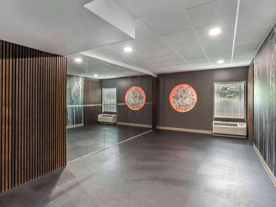 Une pièce moderne et bien éclairée, dotée d’un sol en béton poli, de grands miroirs et de décorations murales de forme circulaire.